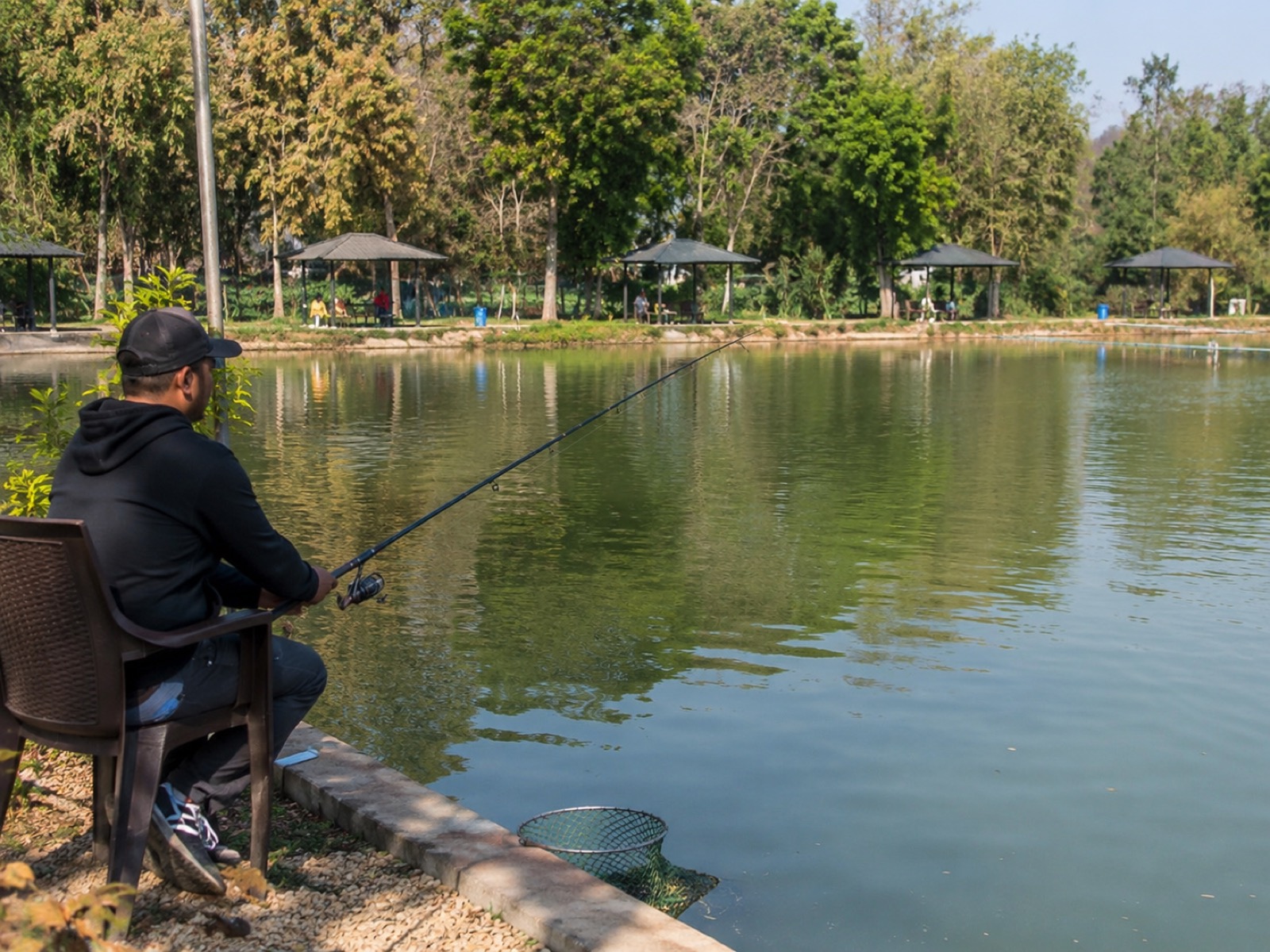 Guest fishing pond-side from a chair, gazebos in the background